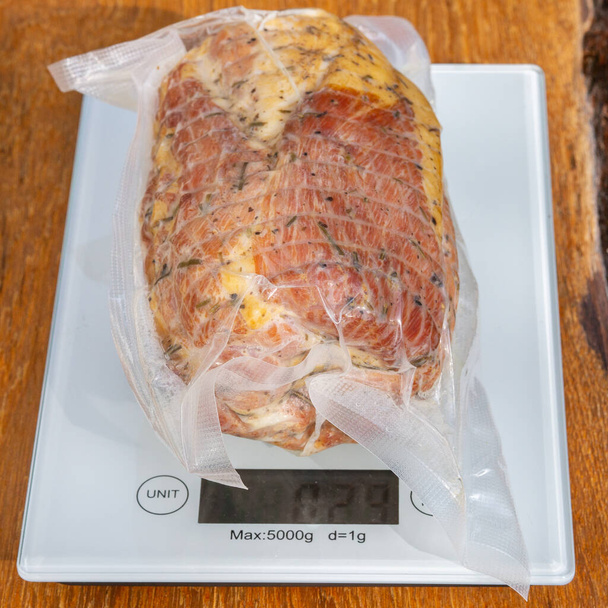 Jambon de porc dans un emballage sous vide scellé sur des balances sur une table en bois gros plan
 - Photo, image