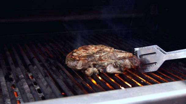 Man turning a piece of grilled meat - Photo, Image
