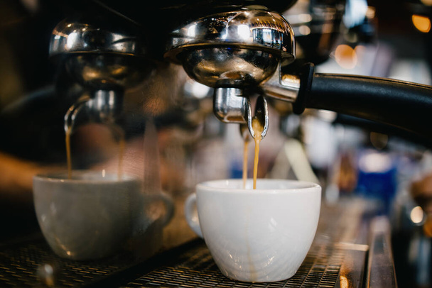 close-up shot van koffiezetapparaat gieten smakelijke, verse en hete koffie in witte beker. - Foto, afbeelding