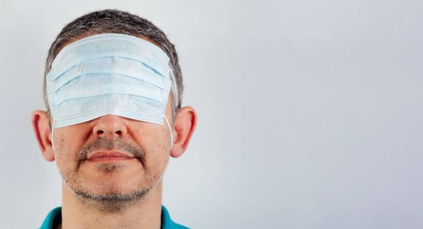 homme isolé les yeux bandés avec masque chirurgical sur les yeux et la bouche et le nez nus
 - Photo, image