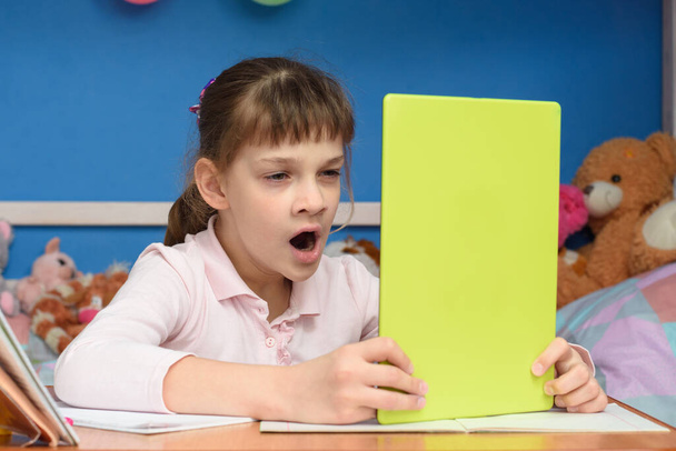 Девушка дома за столом зевает во время просмотра скучного видео-урока
 - Фото, изображение