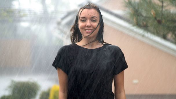 Mujer joven disfrutando de la lluvia en el jardín en el día de lluvia
 - Foto, Imagen