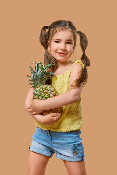 Funny young girl playfully posing with pineapple on beige background - Fotoğraf, Görsel