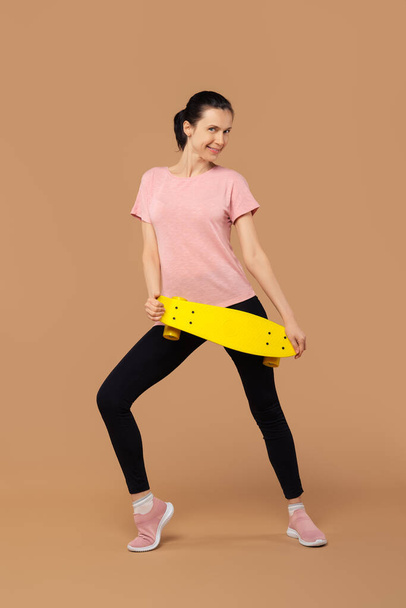 Sportive girl with skateboard over beige background - Photo, image