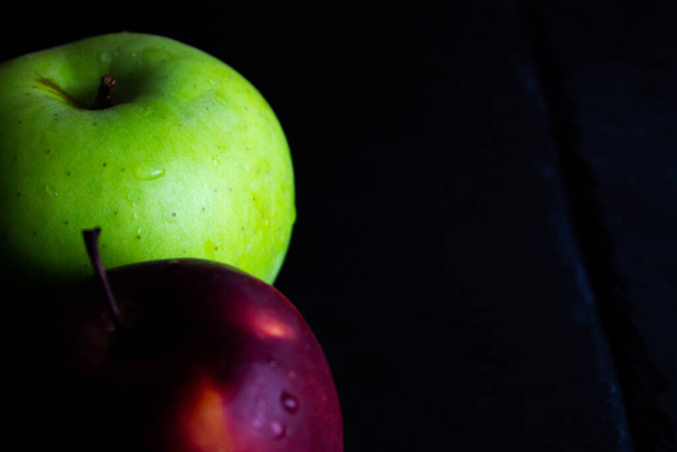 twee verschillende appels op leisteen en rustieke achtergrond - Foto, afbeelding