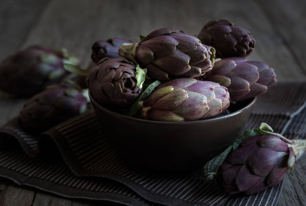 Свіжі неварені артишоки овочі в темній мисці, концепція здорової їжі
 - Фото, зображення