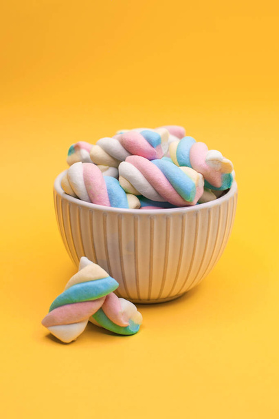 Krásný pohár plný barevných marshmallows bonbóny na žlutém pozadí. Koncept sladkého jídla a dezertů. - Fotografie, Obrázek
