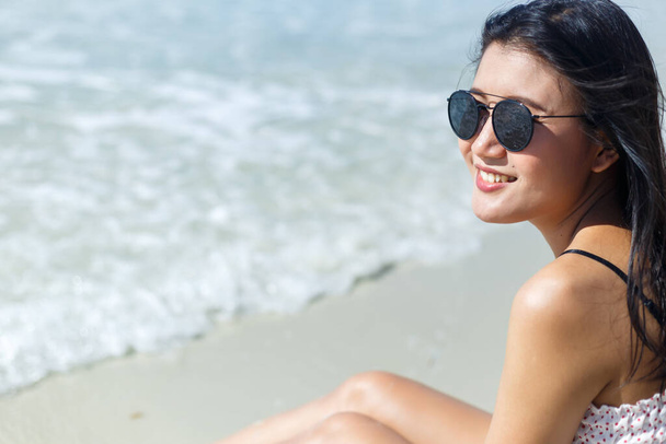 Woman sitting on the white sand beach and enjoy with sea water. - Zdjęcie, obraz