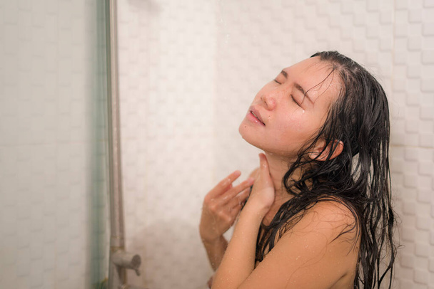 home lifestyle portrait of young beautiful and happy Asian Chinese woman taking a shower in the bathroom washing her hair enjoying morning hygiene in skincare and beauty concept - Фото, изображение