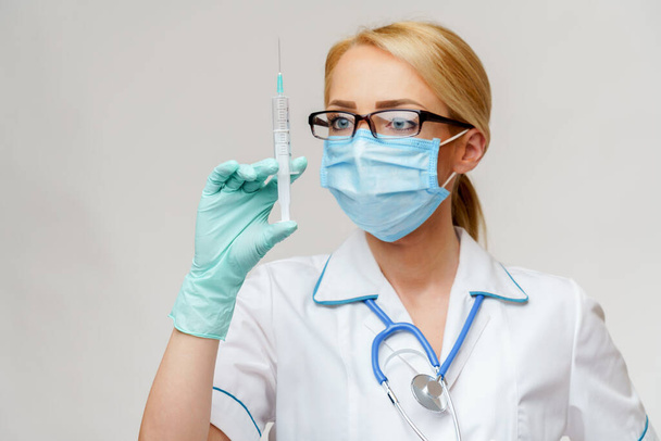 medical doctor nurse woman wearing protective mask and gloves - holding syringe - Foto, Imagem