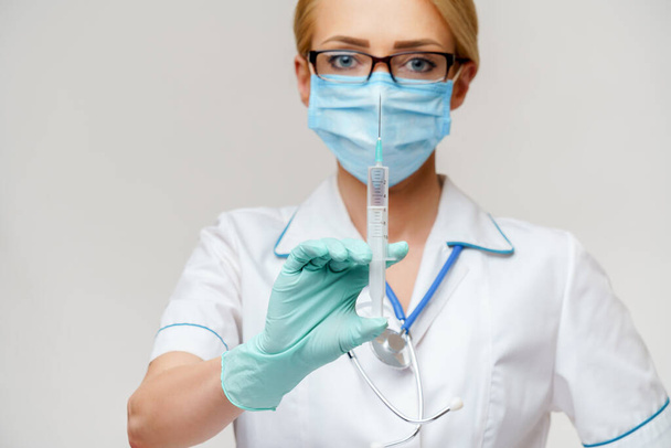 medical doctor nurse woman wearing protective mask and gloves - holding syringe - Fotoğraf, Görsel