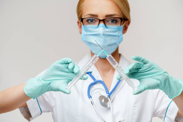 medical doctor nurse woman wearing protective mask and gloves - holding syringe - Fotoğraf, Görsel