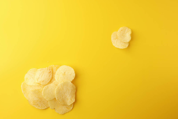 Crispy potato chips snacks on yellow background. Image top view, flat lay, and copy space. - Fotografie, Obrázek