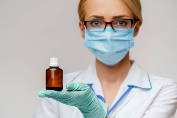 medical doctor nurse woman wearing protective mask and rubber or latex gloves - holding can of pills - Foto, Imagem