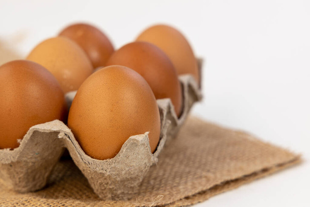 Raw Chicken eggs in cardboard egg box on brow mat. Eggs in the package. - Photo, image