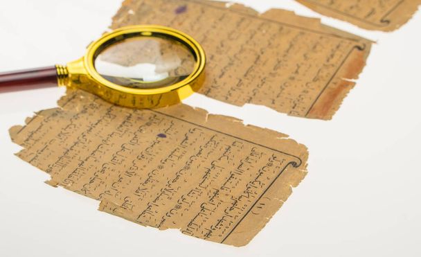 Kniha stránek s arabským rukopisem na stole se světlem a lupou. Paleografie, studium starověkého arabského písma - Fotografie, Obrázek
