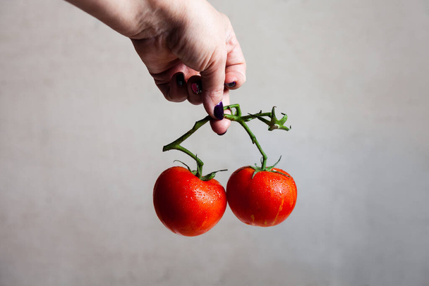 red tomatoes in hand on a grey background - Fotografie, Obrázek
