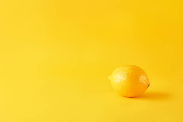 Reife Zitrone auf gelbem Papier. Saftiges Sommervitamin- und Diätkonzept. Minimalismus, monochrom, mit Raum für Text. - Foto, Bild