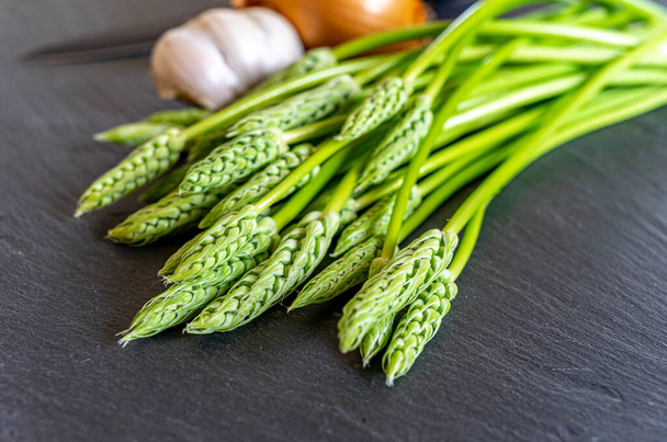 Verse wilde asperges op een lei met knoflook en ui - klaar om te worden gekookt - selectieve focus - Foto, afbeelding