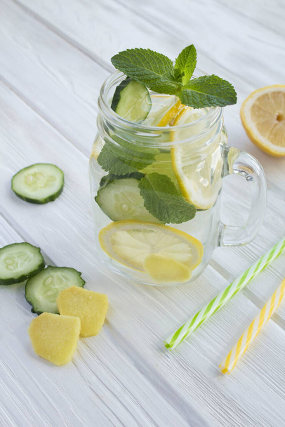 Sassy  water  slimming or infused water with lemon, cucumber and ginger in the glass on the white wooden  background. Location vertical. - Foto, afbeelding
