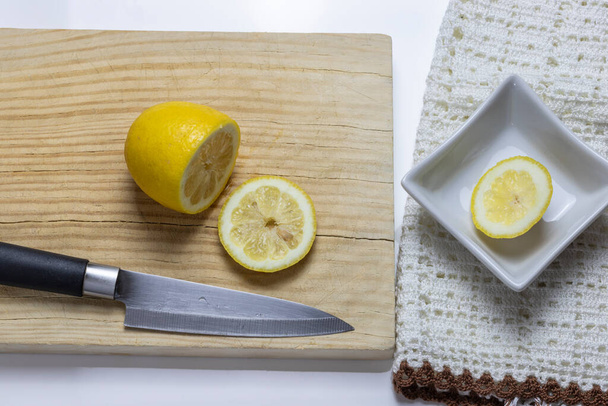 limón cortado con cuchillo en rodajas sobre tabla de madera vieja y sobre fondo blanco
 - Foto, imagen