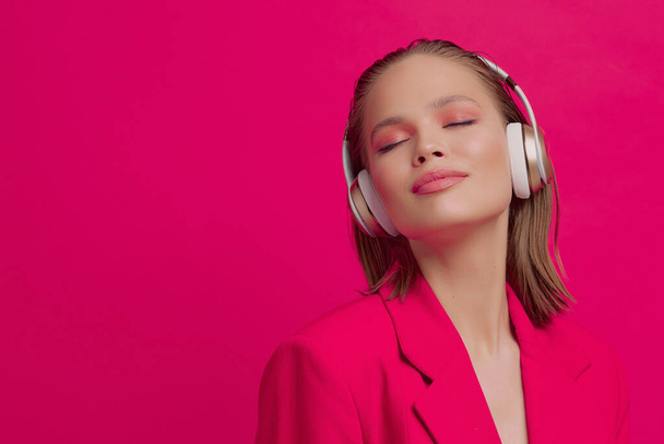 Krásná mladá dívka v bezdrátových sluchátkách poslouchá píseň s dobrou náladou. jasný barevný hudební plakát. - Fotografie, Obrázek