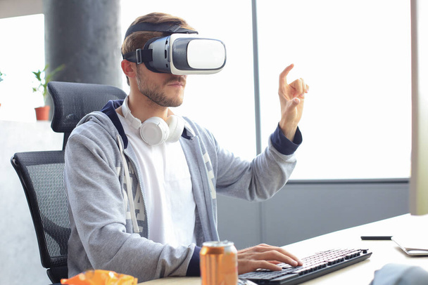 Young bearded man wearing virtual reality glasses in modern interior design coworking studio - Zdjęcie, obraz