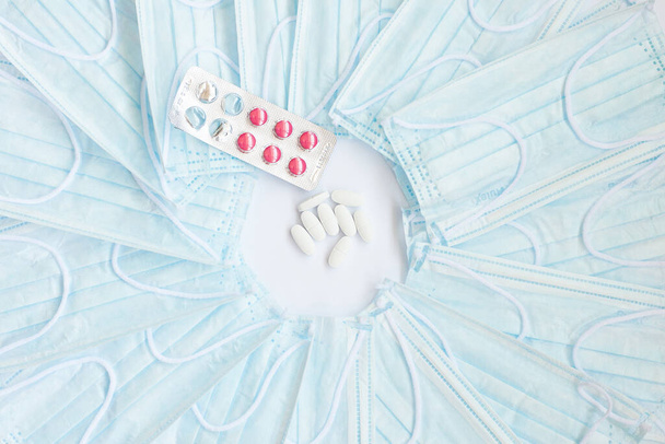 pilules blanches et masques médicaux bleus sur fond blanc
 - Photo, image