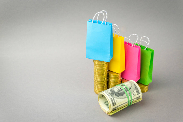 multicolored shopbags standing on smartphone with coins on gray background. Online shopping concept - Foto, imagen