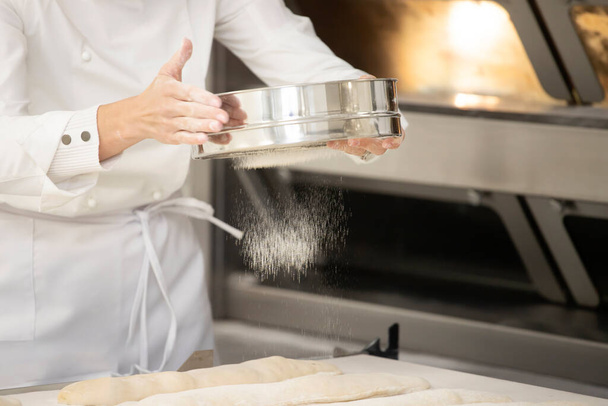 Piekarz pracujący w piekarni tworząc tradycję francuskiego chleba i ciasta. - Zdjęcie, obraz