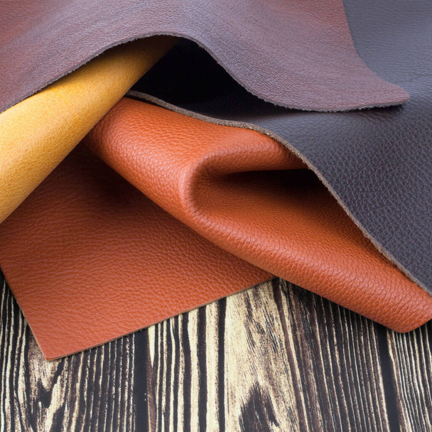 Natural leather textures samples on dark wooden background - Foto, afbeelding