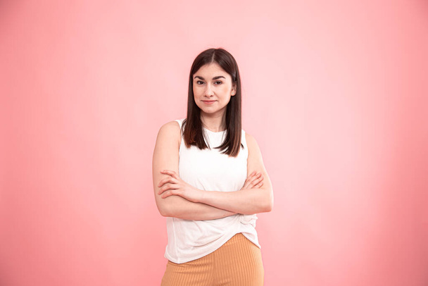 Egy fiatal nő portréja, aki érzelmeket mutat egy elszigetelt rózsaszín háttéren. - Fotó, kép