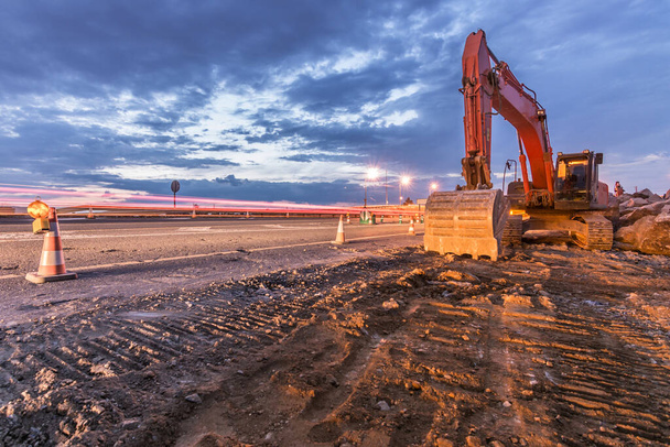 Trabajos de ampliación de una carretera con excavadora y delimitada por conos de seguridad
 - Foto, Imagen