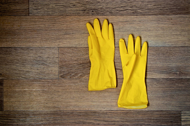 Yellow rubber gloves lie on the wooden floor with copy space - Fotoğraf, Görsel
