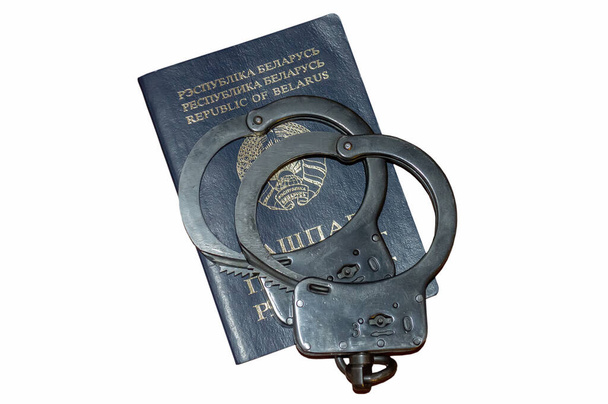 Op het Wit-Russische paspoort staan handboeien, witte achtergrond en isoleren. Het concept: schending van de burgerrechten, politiegeweld, veroordeling van een onschuldige. - Foto, afbeelding
