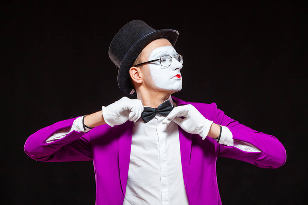 Portrait of male mime artist, isolated on black background. Close up of man face. Man adjusts his bow tie - Foto, imagen