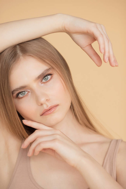 Retrato vertical de una hermosa joven rubia con la piel limpia, fondo beige. Cuidado de belleza cara concepto de moda
 - Foto, imagen