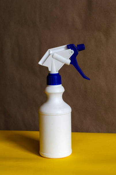 Frasco de plástico blanco con spray sobre fondo bicolor. Botella blanca con corcho azul y gatillo. Vista lateral. Primer plano
. - Foto, imagen