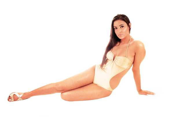 A beautiful young woman in a beige swimsuit sitting in the studio on th - Фото, зображення
