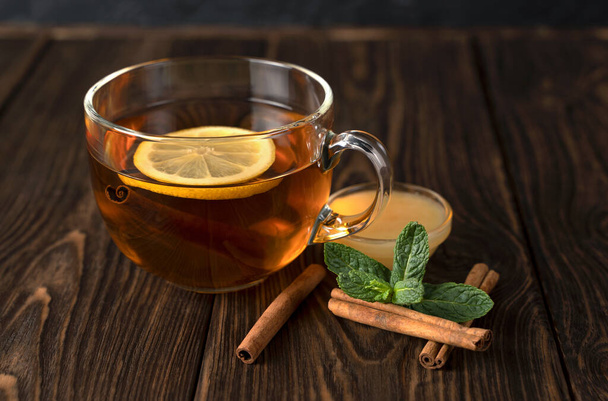 Прозрачный стакан с ароматным черным чаем, мятой, корицей и медом
. - Фото, изображение
