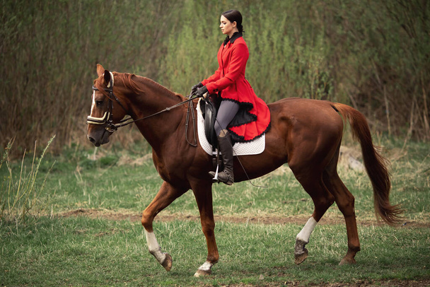 馬術スポーツ、若い女性のジョッキー茶色の馬に乗っている - 写真・画像
