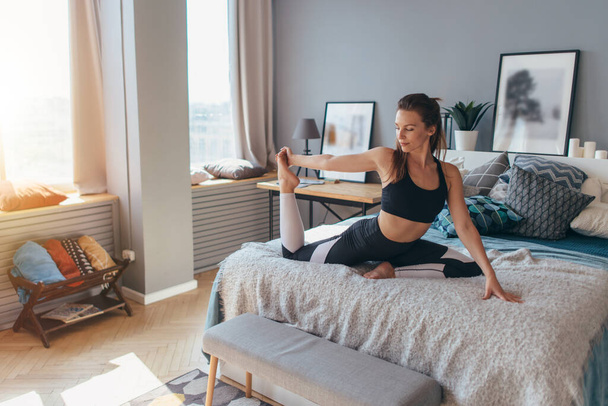 Fit woman doing exercise on bed at home - Foto, Bild