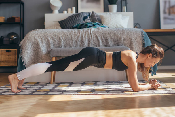 Fitness-Frau trainiert zu Hause mit Unterarmplanke. - Foto, Bild