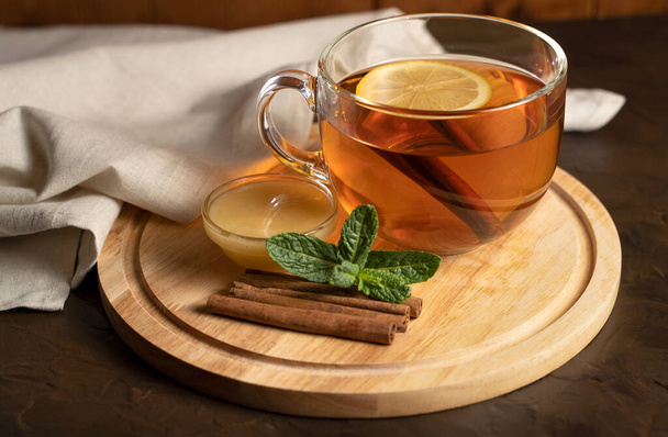 Прозрачный стакан с ароматным черным чаем, мятой, корицей и медом
. - Фото, изображение