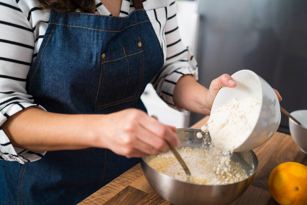 Woman preparing a homemade cake recipe via online in her kitchen - Foto, Imagen