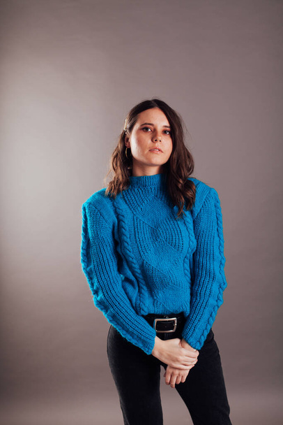 Portrait of a skinny fashionable brunette woman in jeans and a blue sweater - Photo, Image