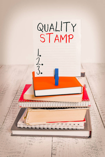 Szóírás szöveg Quality Stamp. Üzleti koncepció a Jóváhagyás pecsétje Jó benyomás Minősített Passed Inspection halom könyvek notebook pin ruhacsap színes emlékeztető fehér fa. - Fotó, kép