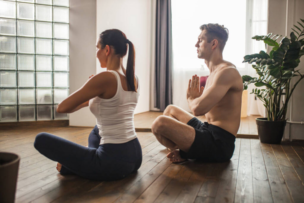 married couple meditating, do yoga exercises at home - Fotó, kép