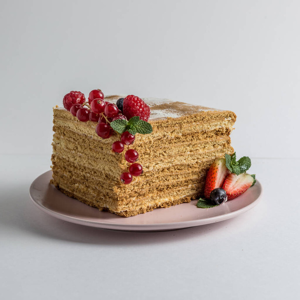 Close up view on honey cake with berries on white plate on white background.  - Photo, Image