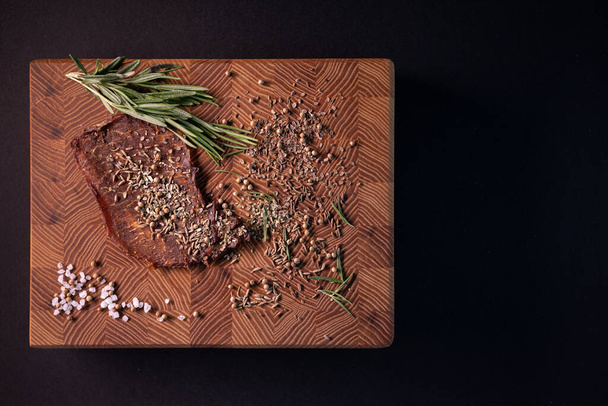 Zbliżenie kawałka mięsa na drewnianej desce z przyprawami. Restauracja menu, seria zdjęć różnych potraw - Zdjęcie, obraz